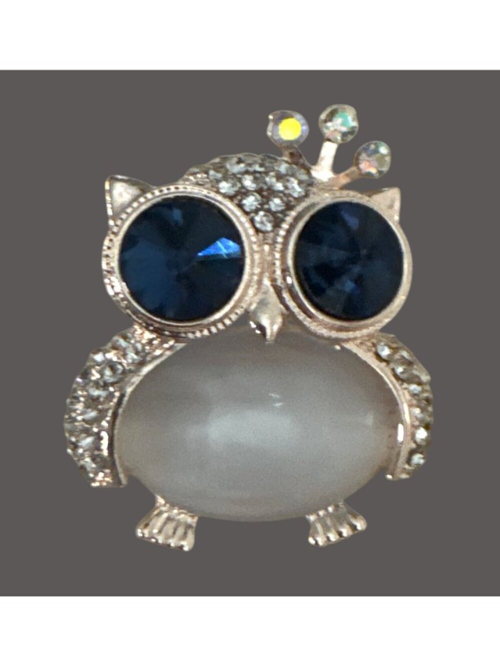 Owl brooch features striking dark blue crystal eyes and milky white cabochon bod